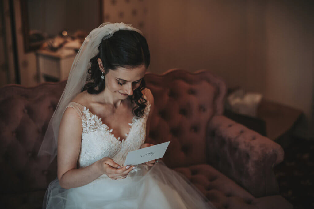 Bride reading letter from her soon to be husband, sitting on a victorian couch in the carriage house of the Woodruff Fontaine House Museum.