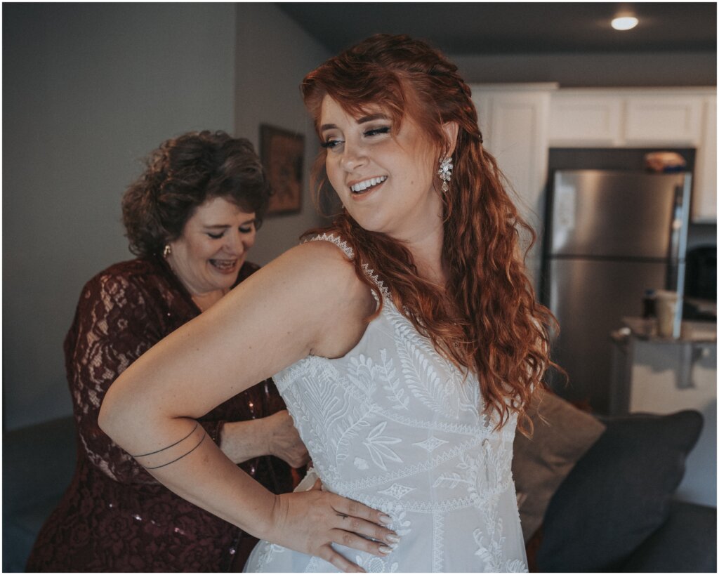 a mother helps her daughter zip up her wedding dress in fayetteville ar