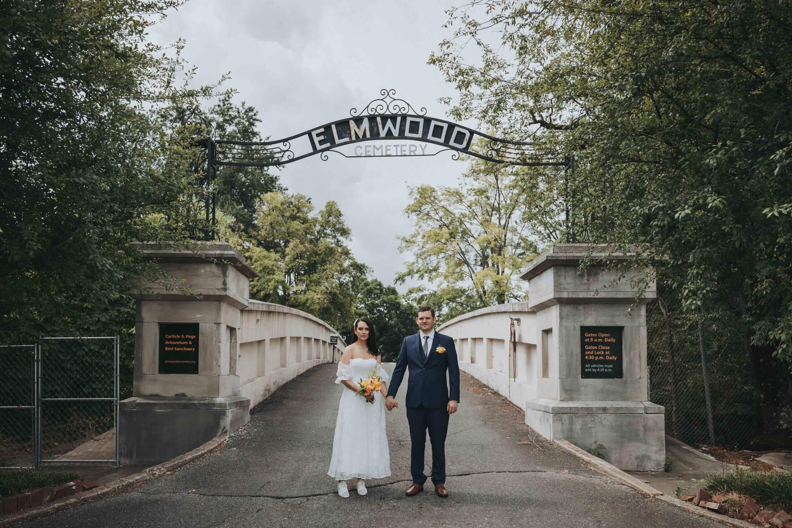 Newlywed couple stands at the entrance of Elmwood Cemetery, where they have just eloped.