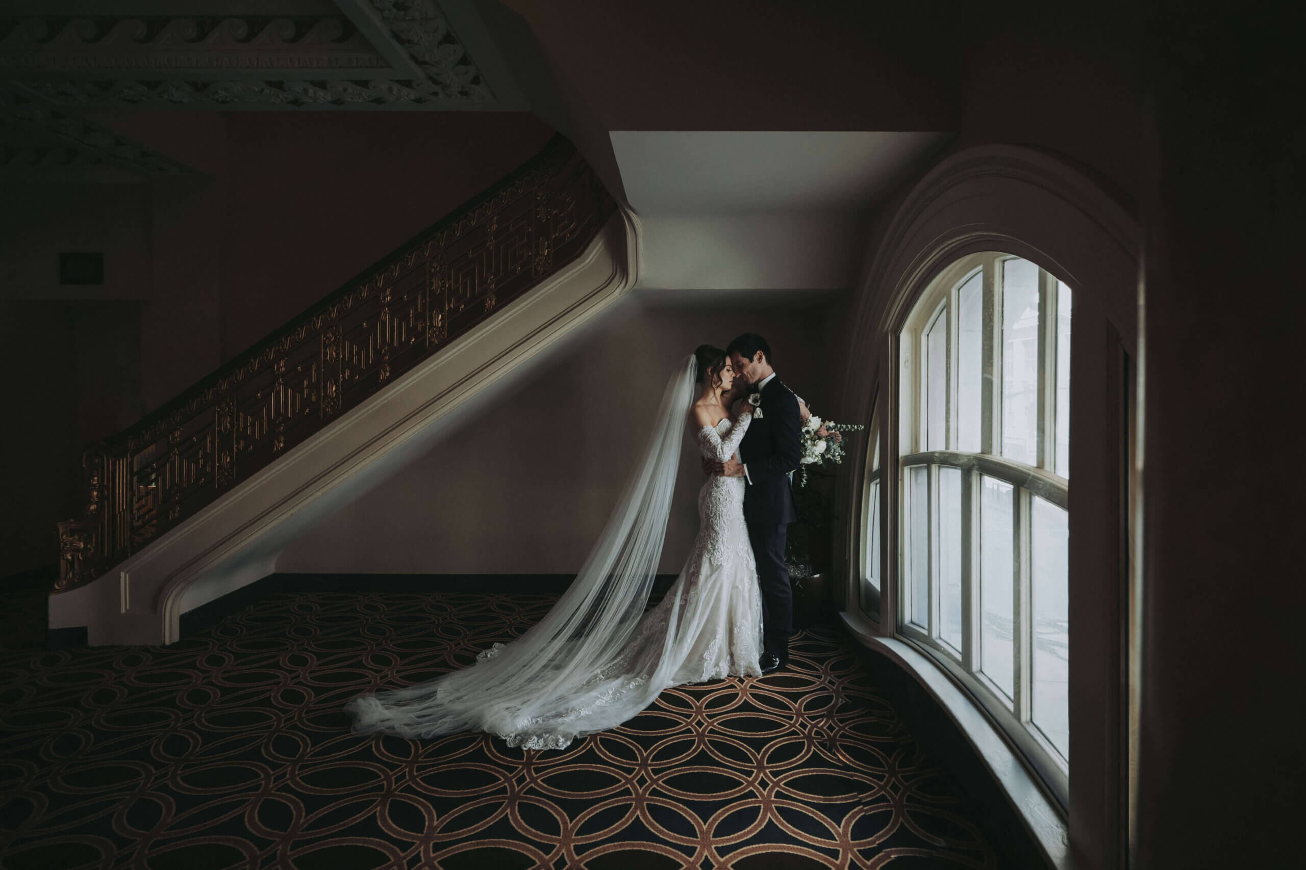 Bride and Groom stand close to each other next to a grand window at the Seelbach Hotel